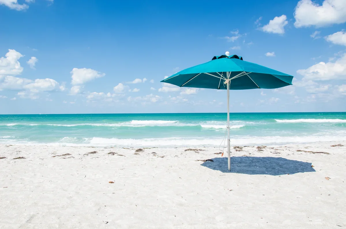 Turquoise beach umbrella on the white sand beside the Gulf at Casa Del Mar