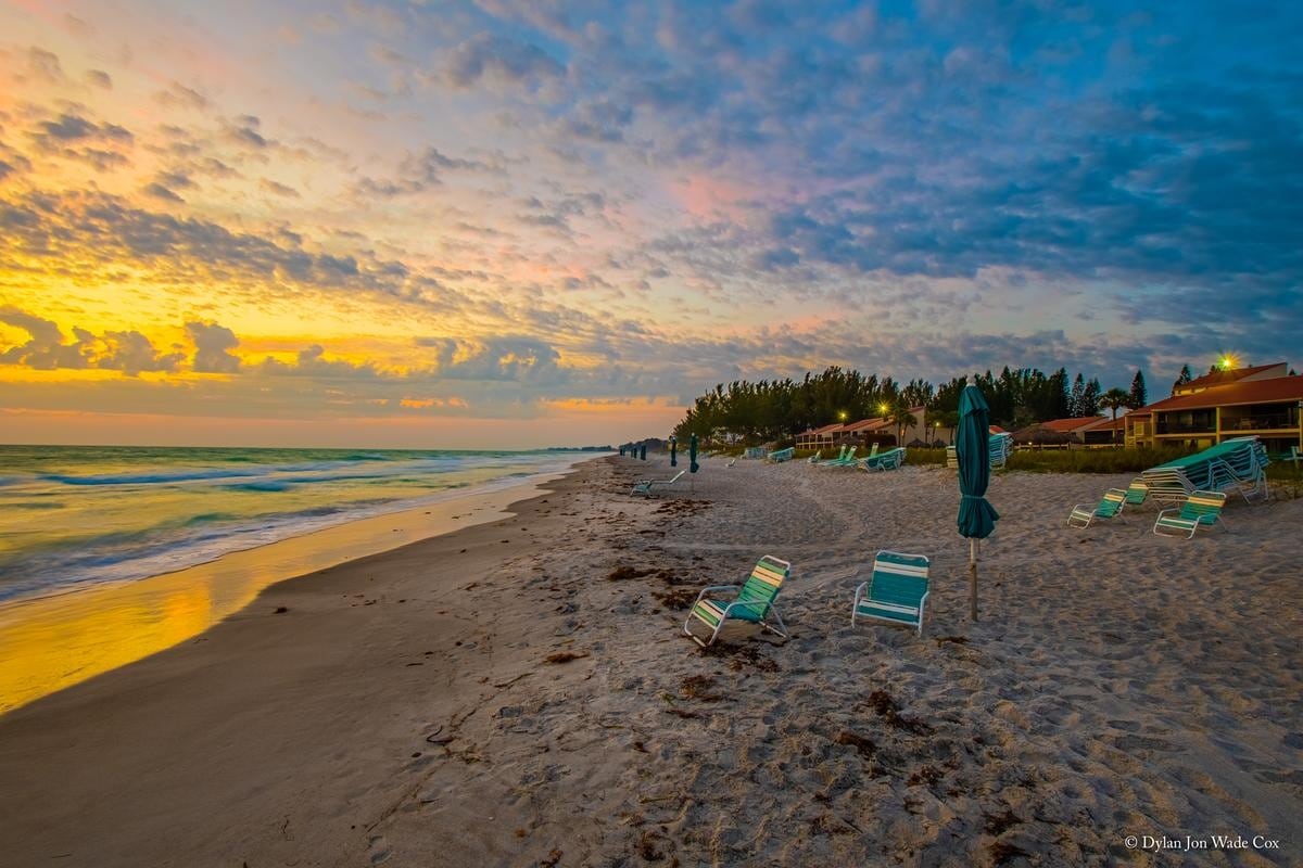 Beach chairs on white sand facing the Gulf sunset at Casa Del Mar