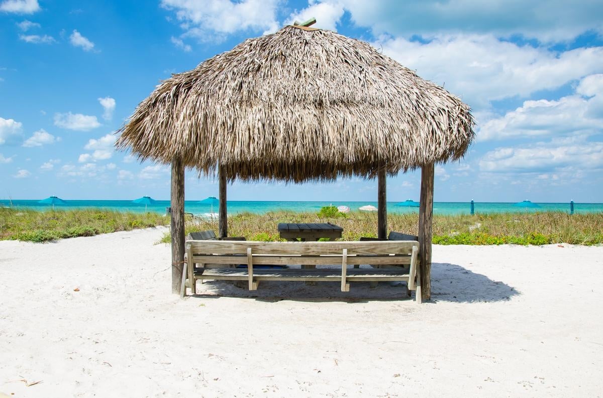 Thatched beachside cabana and chairs overlooking the Gulf at Casa Del Mar