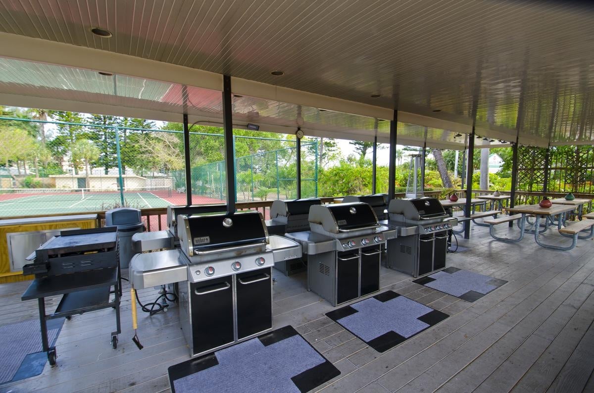 Covered grills and outdoor dining tables beside the Casa Del Mar tennis courts