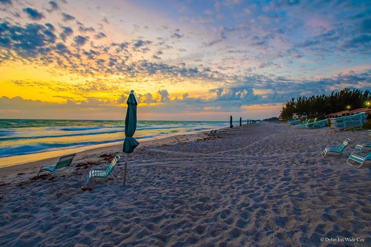Beach chair and closed umbrella facing the Gulf sunset at Casa Del Mar